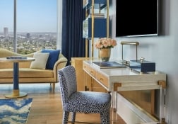 Interior of a room available at The Sun Rose with a desk and chair and a lounging couch in the background in front of views of West Hollywood