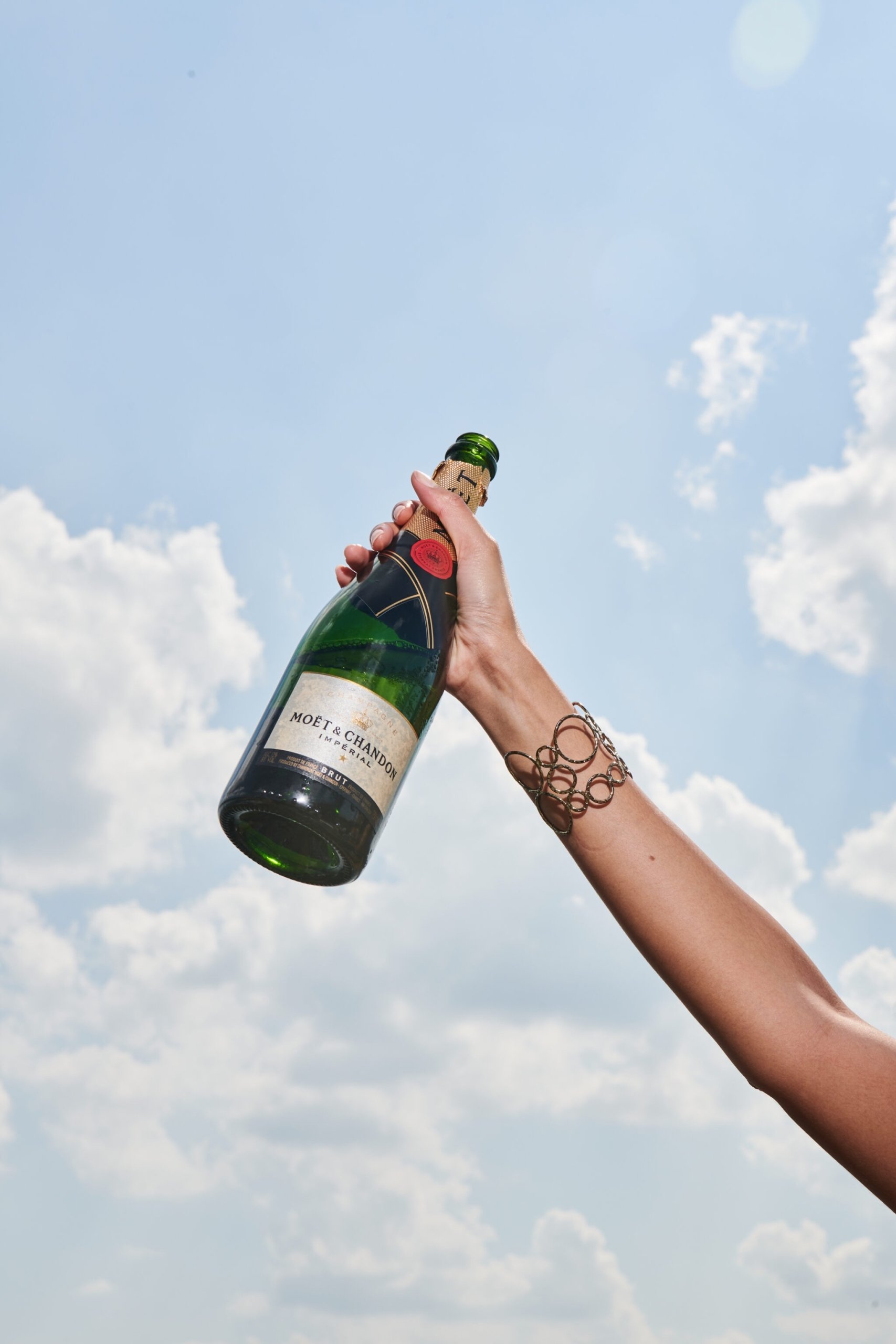 Someone holding up a bottle of Moët & Chandon Champagne into the sky at The Sun Rose