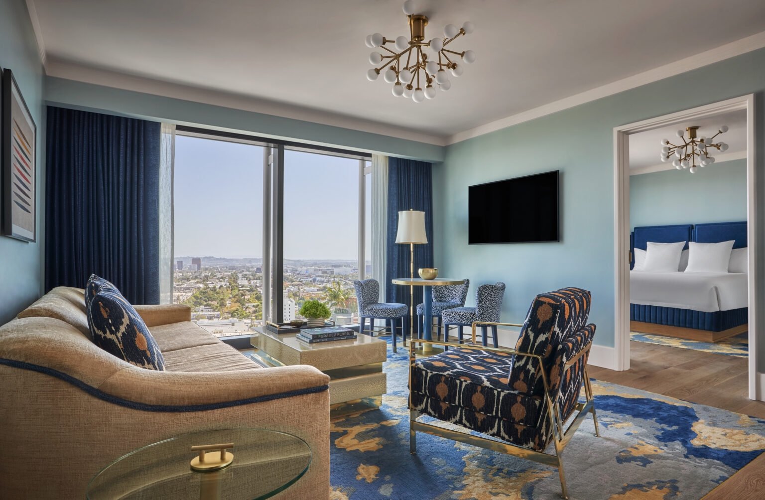 Interior view of a living room at The Sun Rose with a couch and table along with views of West Hollywood in the background