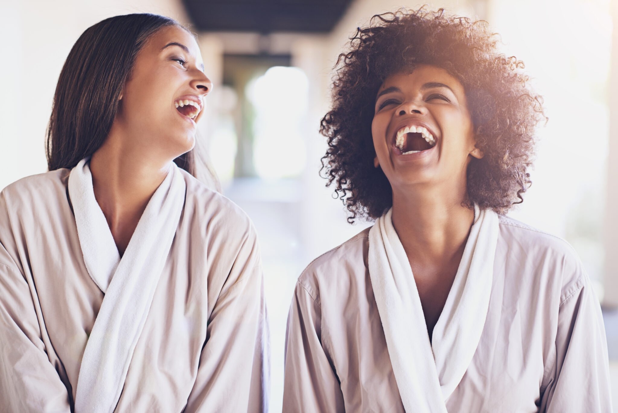 Two women laughing while wearing robes at The Sun Rose