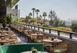 A dining area at The Sun Rose with tables and chairs lined up against the wall overlooking West Hollywood
