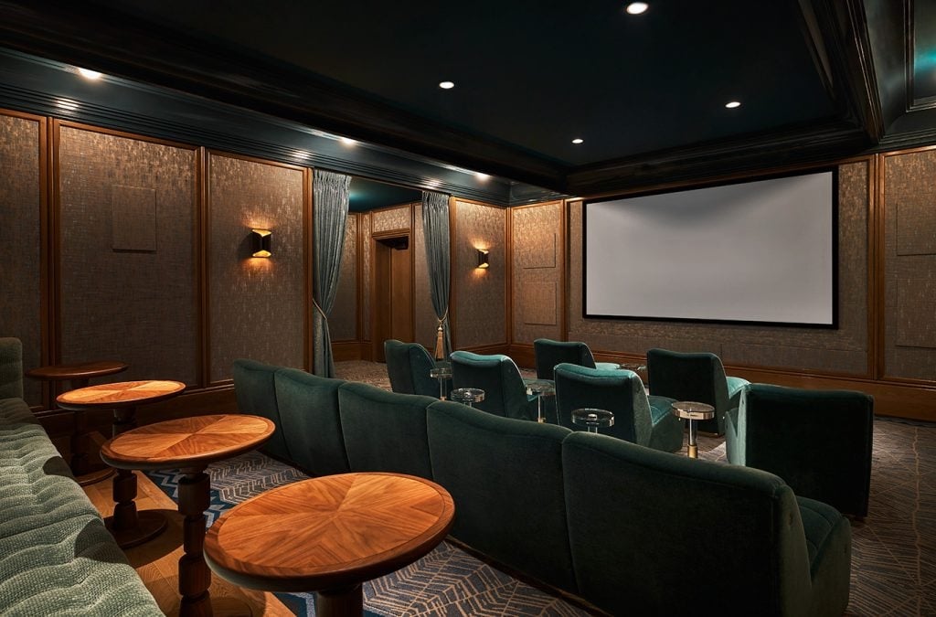 Private theater area at The Sun Rose with tables and chairs and a large projector screen