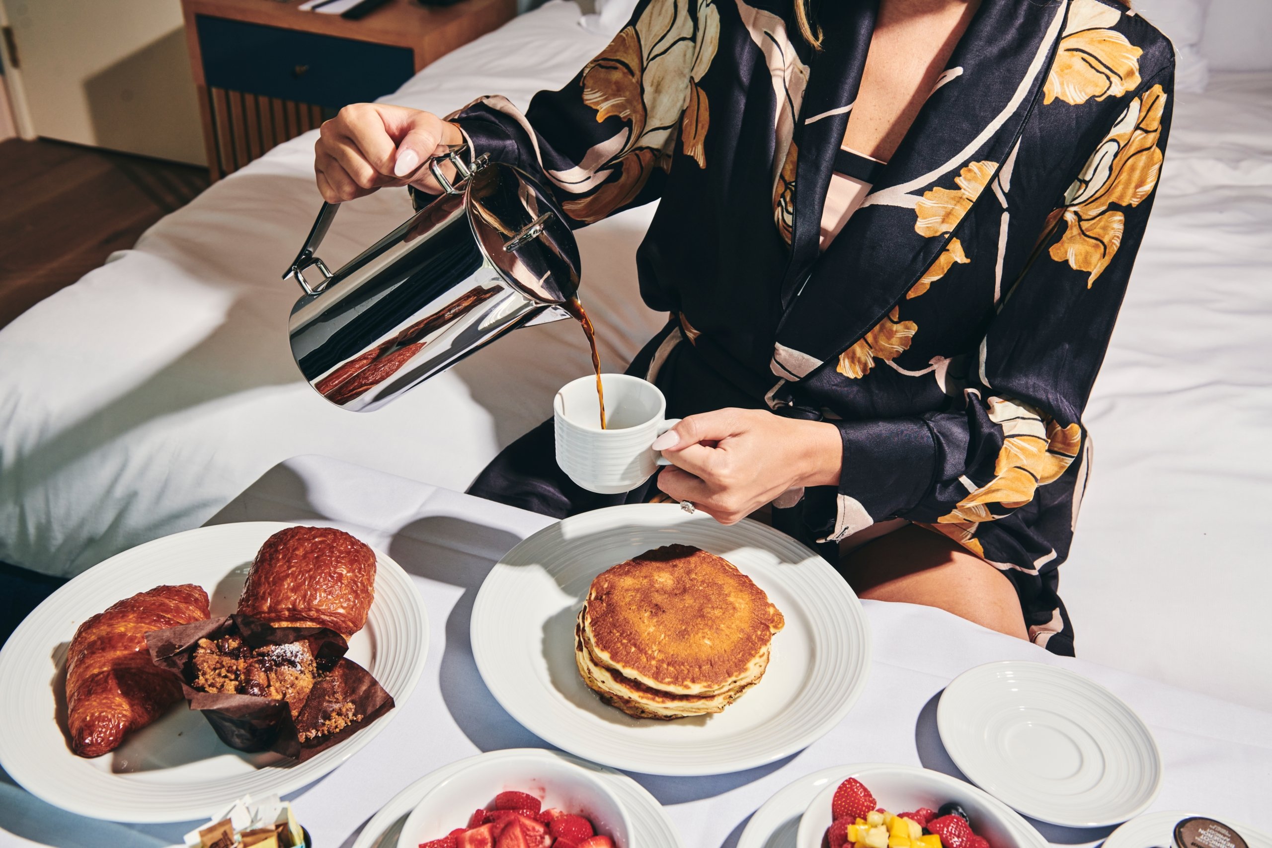 A woman pouring a cup of coffee and enjoying breakfast at The Sun Rose