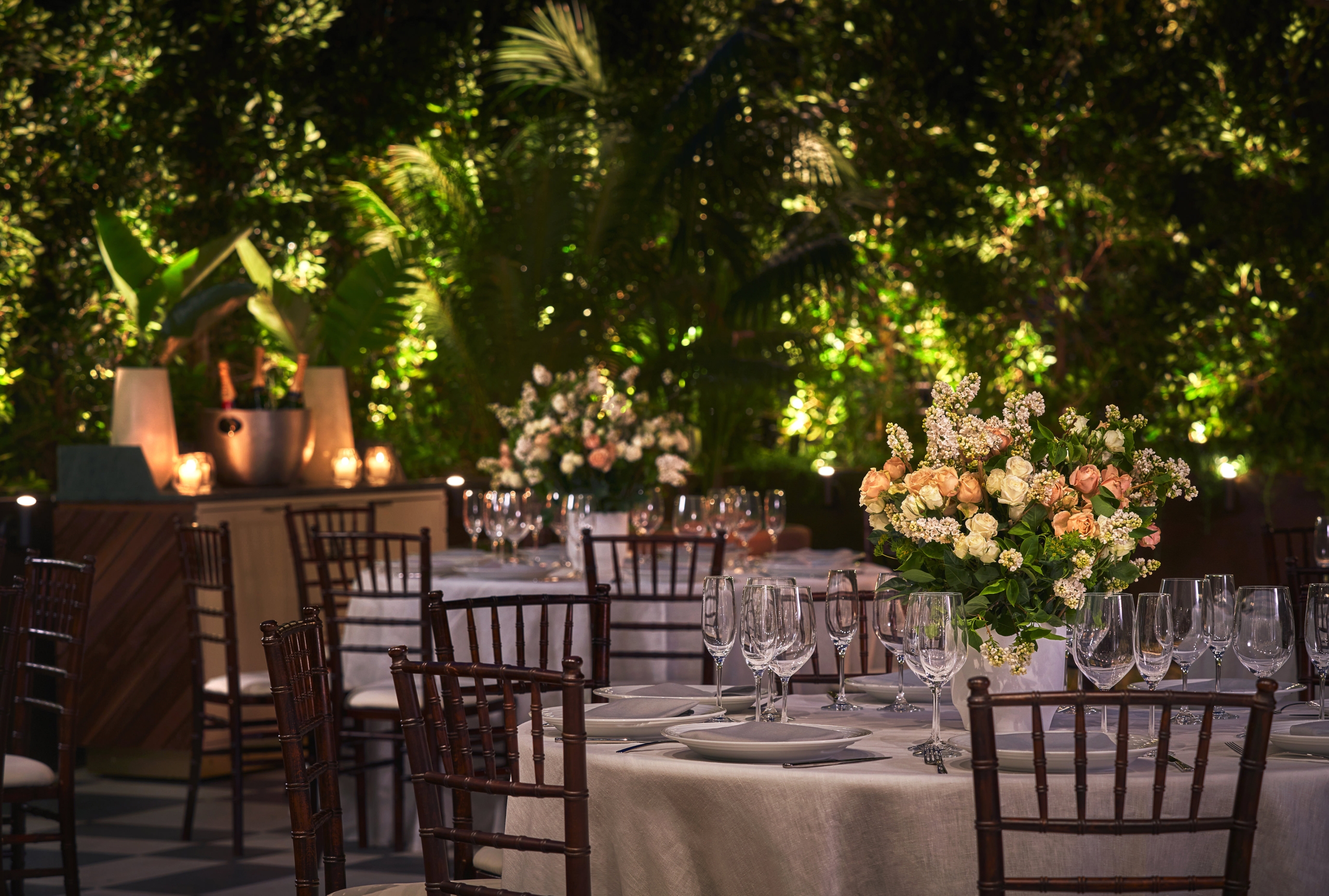 Close up of a table prepared for a wedding service at The Sun Rose, decorated with white linen, plates, cutlery, wine glasses, and a large floral bouquet as the centerpiece