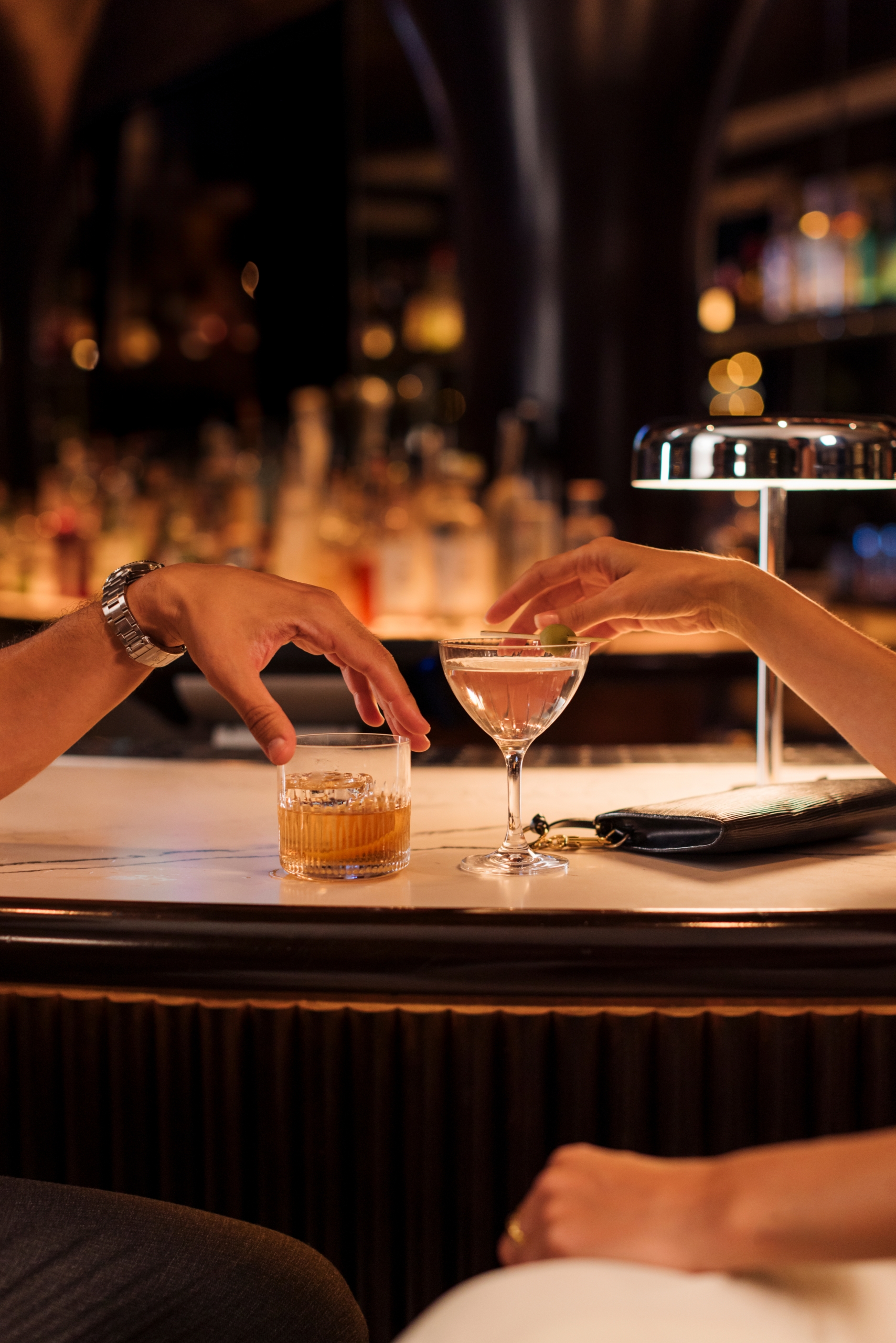 Close up of two drinks with a man and woman's hand grabbing each at Ritual, The Sun Rose lobby bar