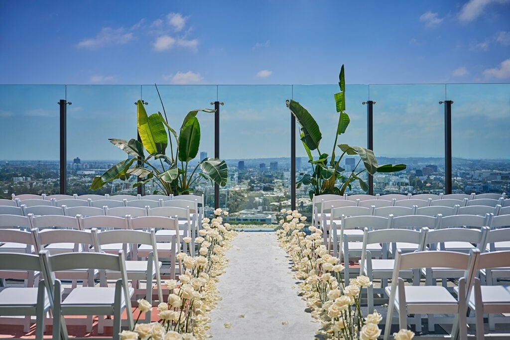 Outdoor wedding service with chairs and aisle set up on the rooftop, with views of West Hollywood in the background.