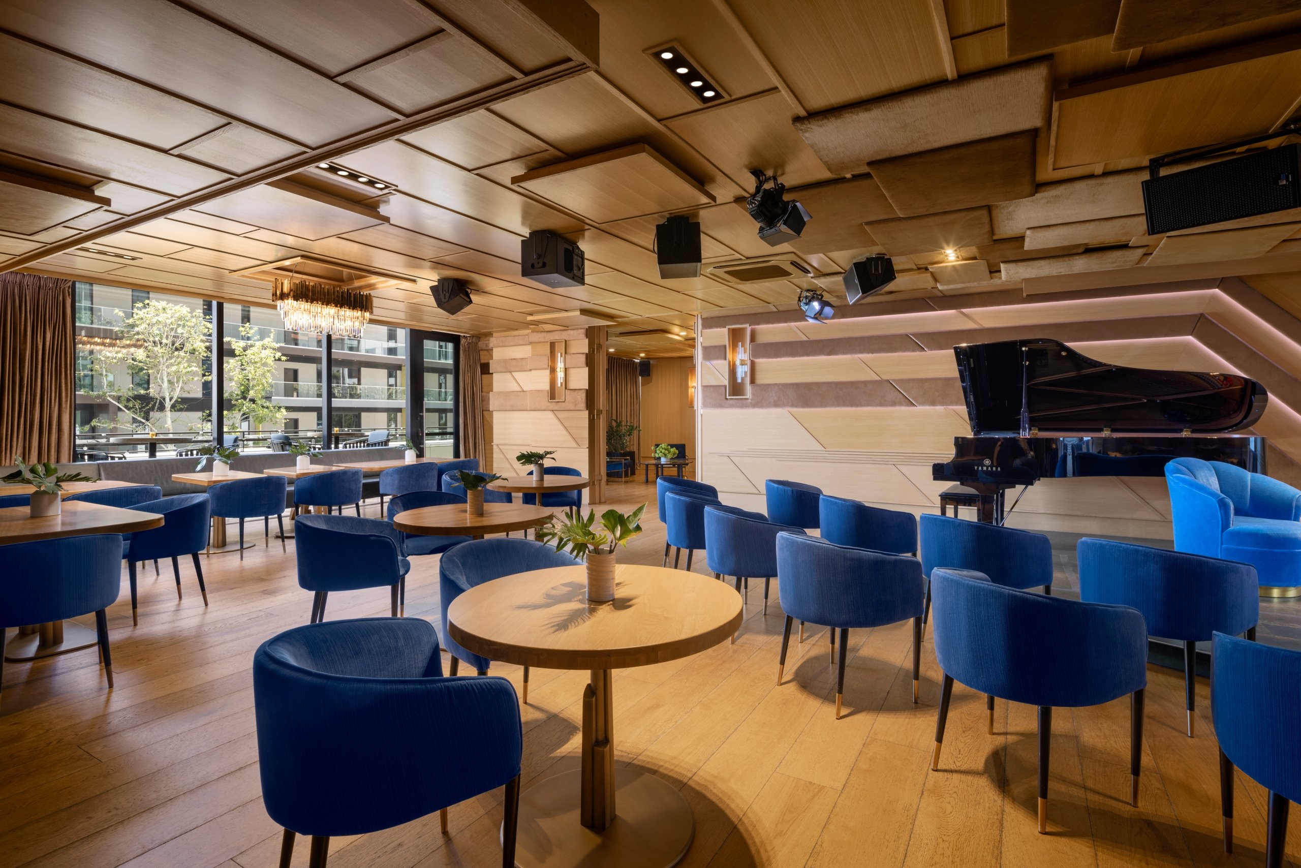 A dining area in The Sun Rose with tables along the wall and a large grand piano in the center