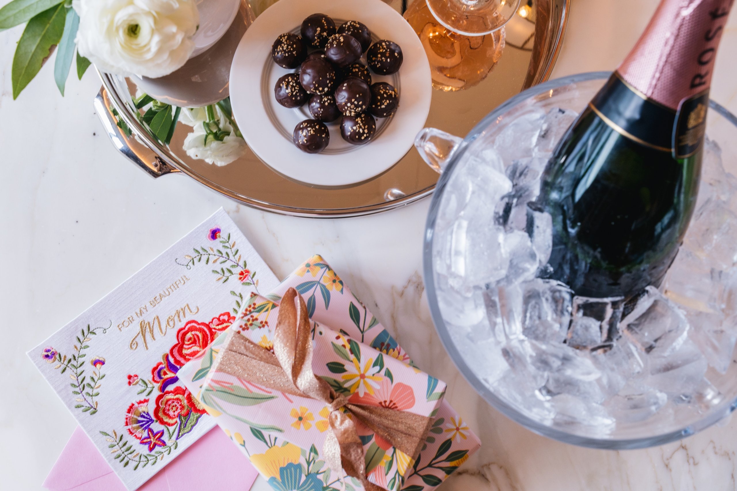 Close up of a bottle of champagne in a bucket of ice and chocolates with mothers day gifts at The Sun Rose