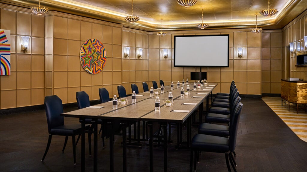 Large meeting space with lots of table space and chairs and a projector screen at The Sun Rose