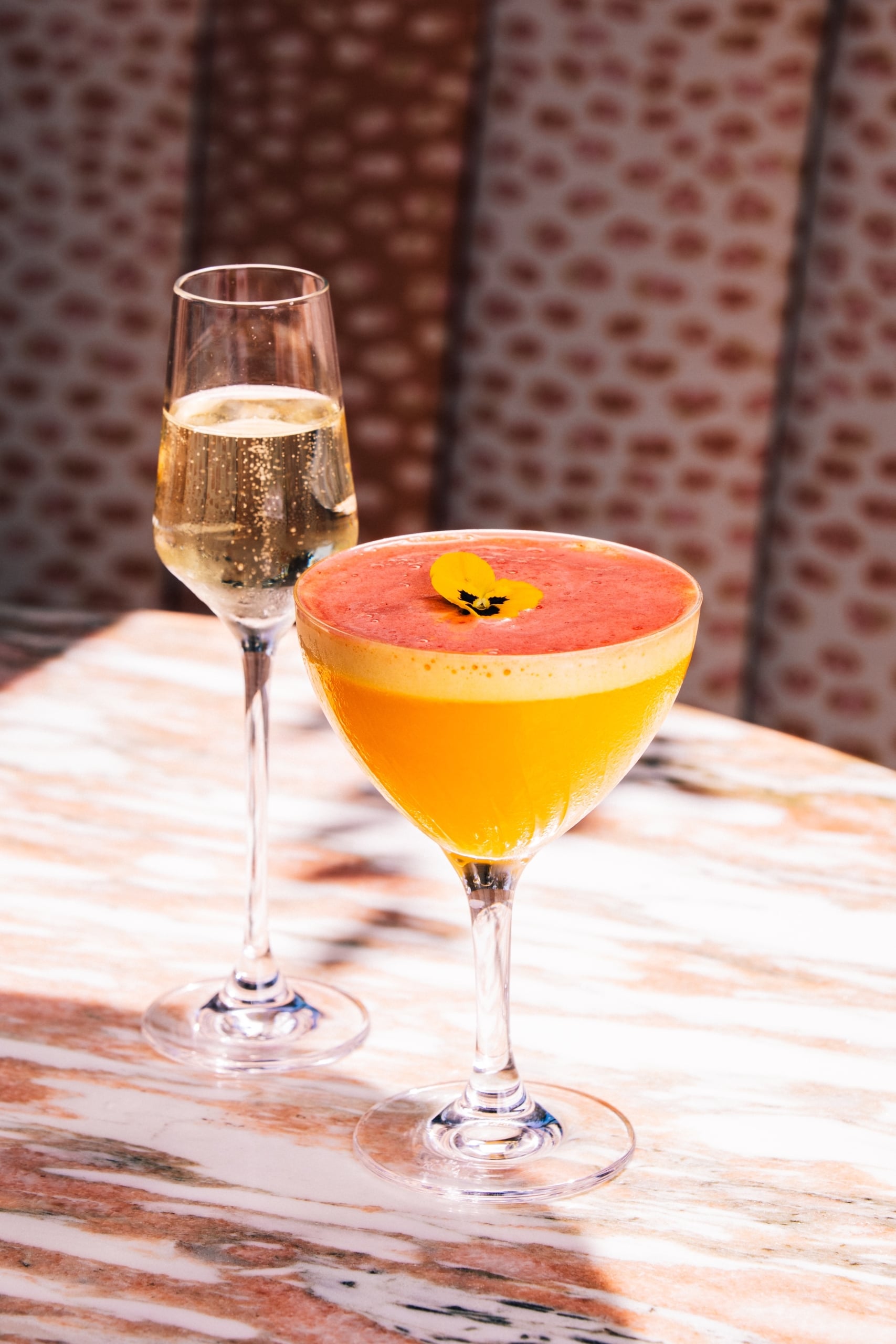 A glass of champagne and a scarlet horizon cocktail.